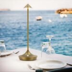 Gold cordless table lamp with dimmer on outdoor dining table.