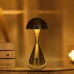 Modern mushroom table lamp on desk creating a warm glow.