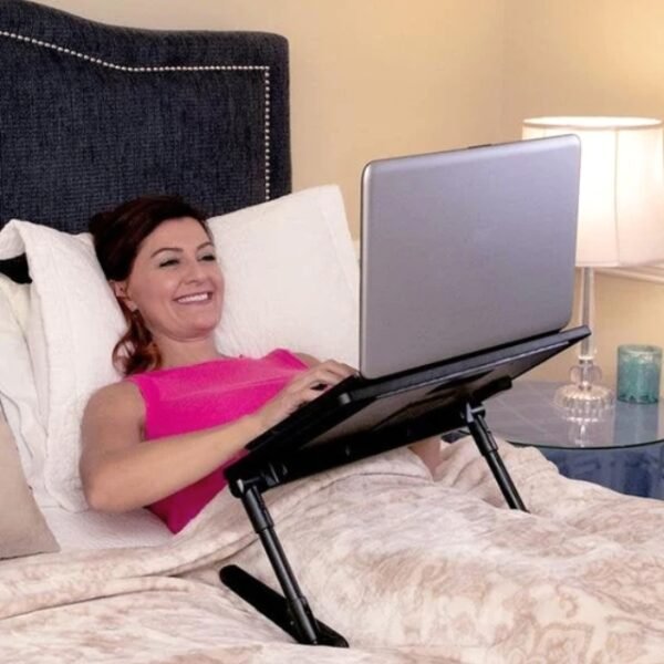 Woman reclining on bed with Air Space laptop table.