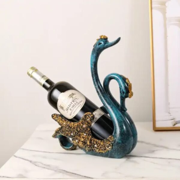 Blue Couple Swan Wine Holder decorates a counter, holding a vintage bottle.