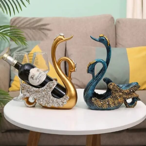 Swan wine holders in blue and gold face each other on a table with precious stones.