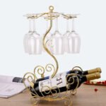 Golden vine wine rack on table holding two bottles and six glasses with vine design.