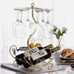 Golden vine wine rack on kitchen counter holding two bottles and six glasses in gold finish.