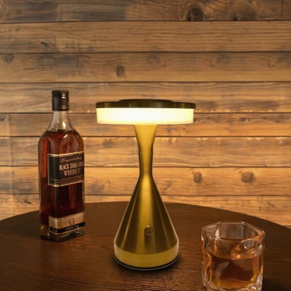 Hourglass table lamp creating a cozy glow next to a bottle of alcohol.