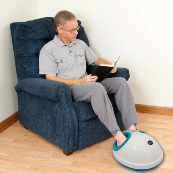 Man reading a book while using the Igia foot spa massager in the living room.