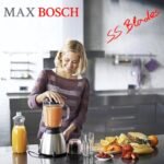 Woman using Max Bosch blender in her kitchen with a smile.