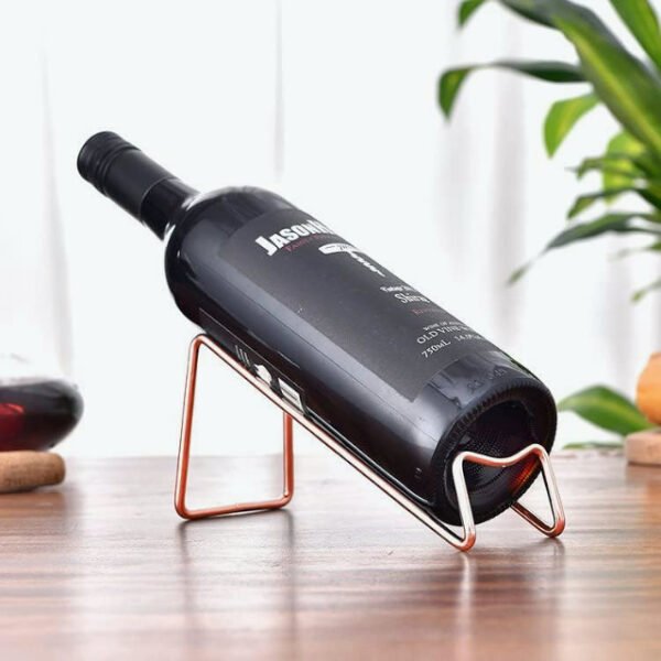 Minimalist wine bottle holder with rose gold finish on table.