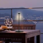 Nordic table lamp in black casting warm light outdoors on a dining table with stepless dimming.