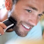 Man smiling and grooming his beard while using the Philips 3000 series trimmer. Suitable for styling and creating perfect stubbles.