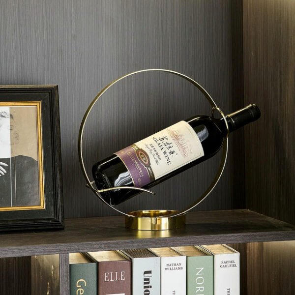 Round wine bottle holder in book library with shiny gold finish.