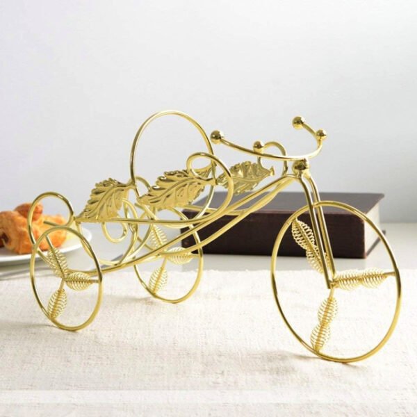 Gold tricycle wine holder on a dining table, showcasing durable iron construction.