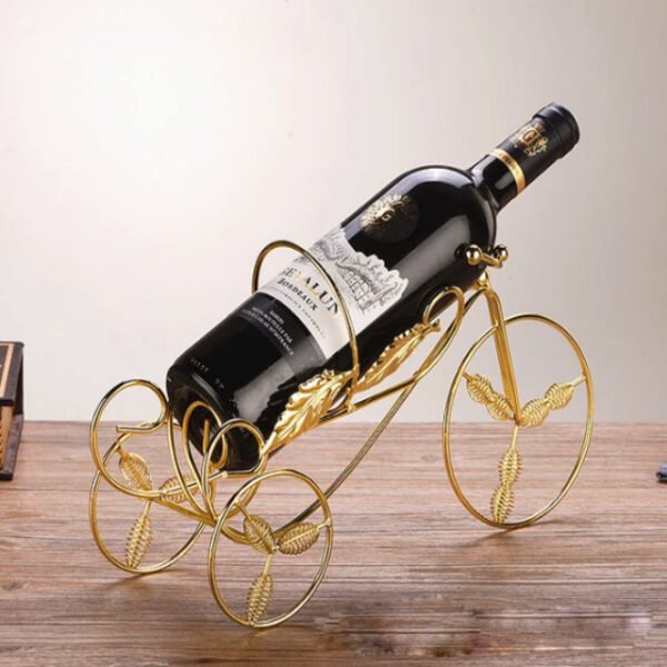 Tricycle wine rack in gold holding a wine bottle on a table.