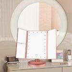 Superstar makeup magnifying mirror in pink on bedroom table, displaying its sleek design.