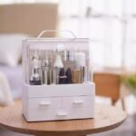 Fashionable makeup storage box on wooden table, sleek design, top handle, large compartment, three shelves.