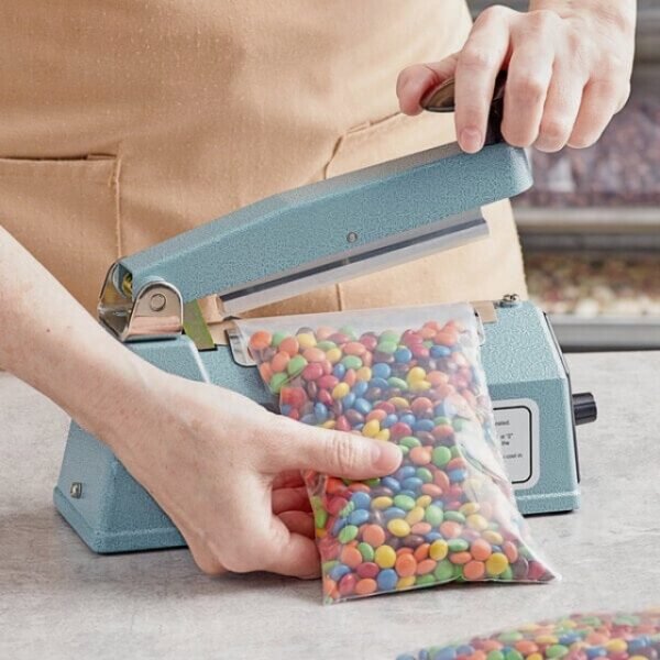 Manual Impulse Sealer - Man sealing M&M's bag.