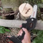 Mini cordless chainsaw efficiently chopping a tree in two.