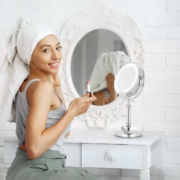 Woman happily using LED-lit Orbegozo makeup mirror for lipstick.