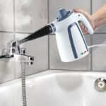 Woman using Switch-On steam cleaner in bathroom, with special nozzles for tight spots.