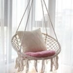 Swing hammock chair in bedroom with pillows for ultimate relaxation.