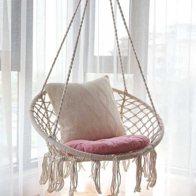 Swing hammock chair in bedroom with pillows for ultimate relaxation.