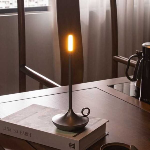 Aladdin table lamp in silver on book for reading.