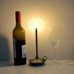 Aladdin table lamp in black next to champagne bottle and glass.