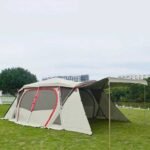 Light khaki and red large camping tent outdoors with sunroof open.