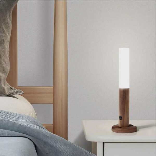 Dark brown motion sensor night light casting warm illumination on bedside table.