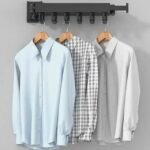 Foldable clothes drying rack holding clean shirts indoors.