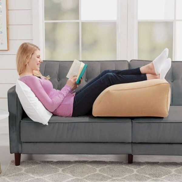 Woman enjoying a book while using BulbHead inflatable leg cushion.