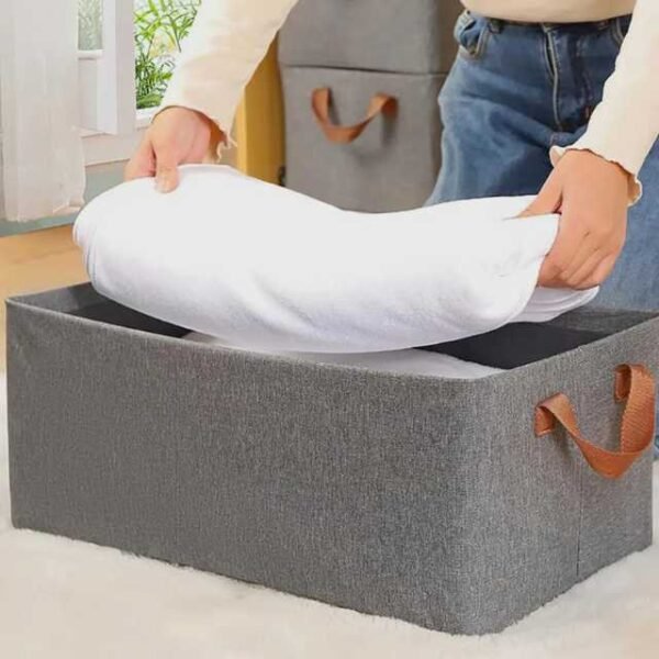 Woman folding clothes and placing them into a cloth organizer box.