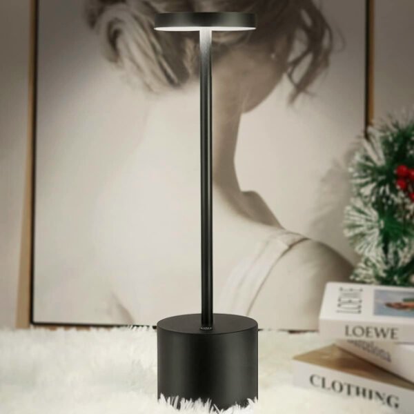 Black modern table lamp on a table casting warm light in a home setting.