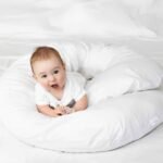 Baby sitting comfortably in the C-shaped maternity pillow.