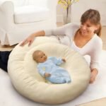 Happy mom watching baby sleep in padded maternity pillow bed.