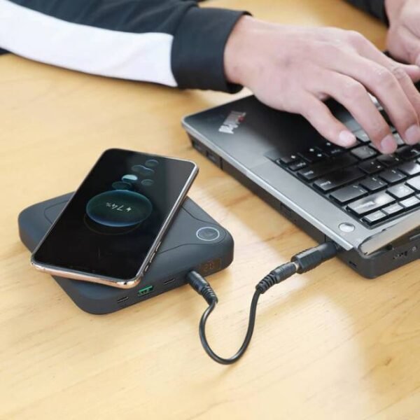 Man charging laptop and phone simultaneously using power bank.