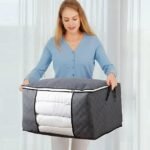 Woman using side handles of foldable storage bag for transport.