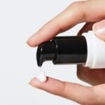 Woman dispensing COSRX under eye cream onto her finger for application.