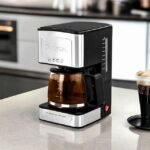 Lexical American coffee maker brewing coffee on kitchen counter with modern design.