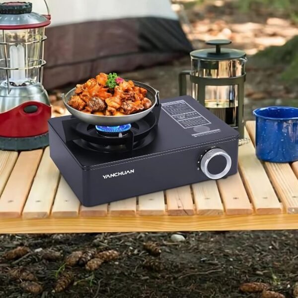 Camping stove outdoors on wooden table cooking a quick meal.