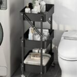 Black storage cart placed between a washing machine and a toilet, storing toiletries, towels, and other essentials.