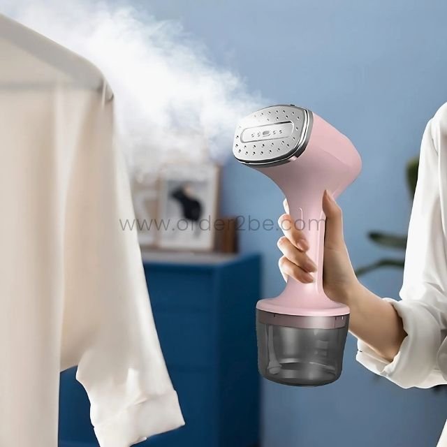 Woman using the pink portable garment steamer to smooth out wrinkles from a shirt.