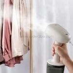 Using the portable garment steamer on hanging clothes to remove wrinkles.