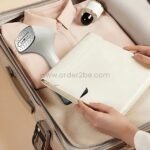 portable garment steamer packed in suitcase with folded clothes.