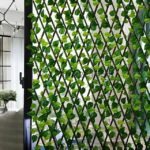 Green leaf trellis in front of a glass door, adding greenery and privacy with its diamond-patterned lattice structure.