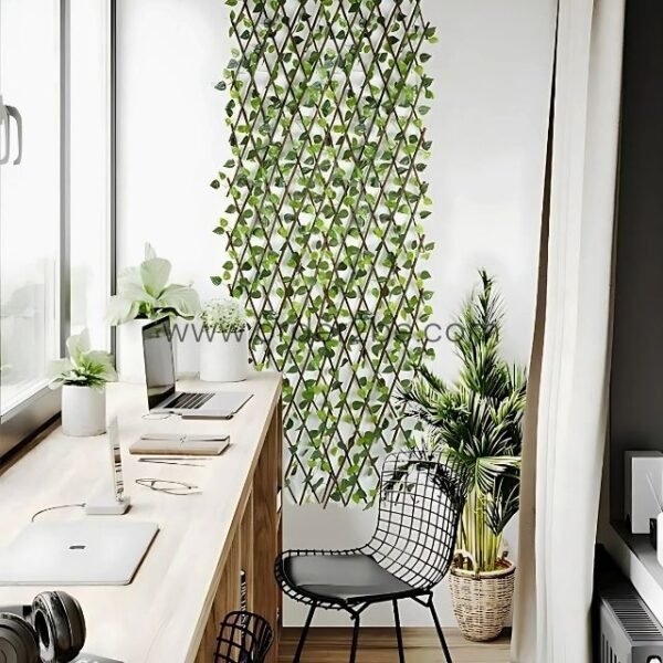 Minimalist workspace with a wooden desk, laptops, and a black chair. Behind, a green leaf trellis adds a touch of nature to the clean, organized setting.
