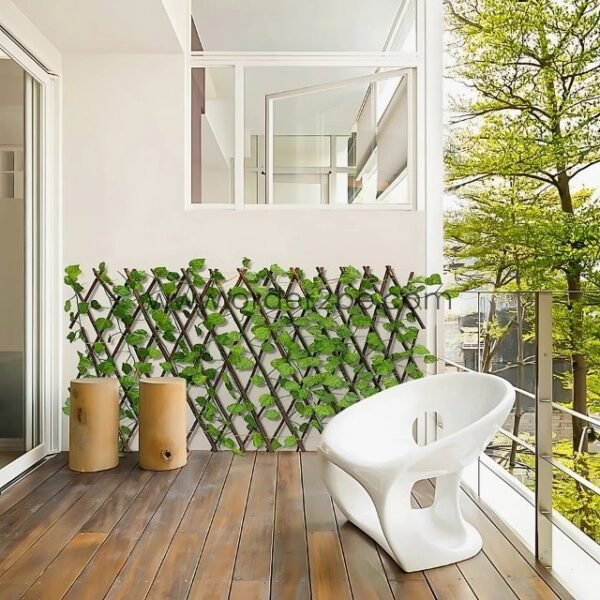 Modern balcony with a wooden floor, featuring a green leaf lattice structure, white chair, and wooden stools, offering natural decoration and privacy.