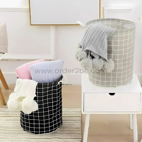 Black and grey storage baskets holding pastel pillows and pom-pom blankets in a tidy room setting.