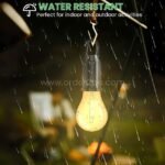 Water-resistant LED light bulb with hook, illuminated in rain, designed for outdoor use and unpredictable weather.