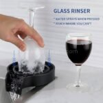 A hand pressing a wine glass onto the automatic cup and glass washer, activating its powerful water jets.