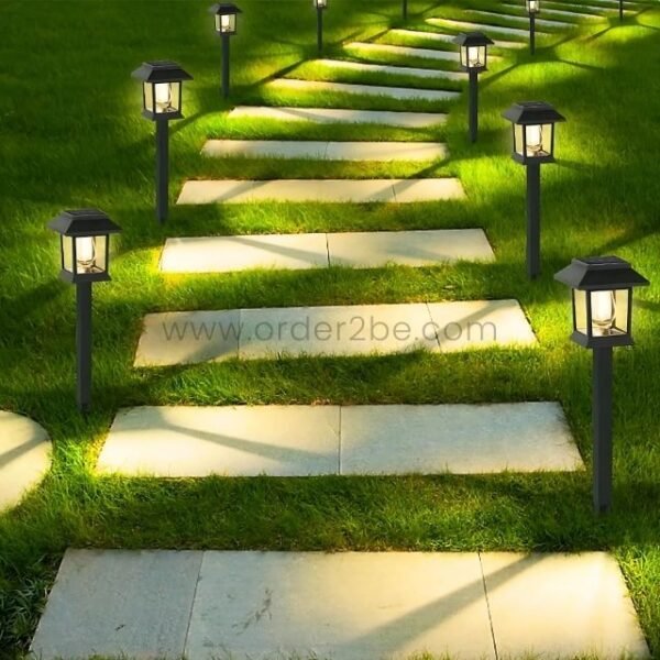 Solar garden pathway lights bordering a stone pathway, casting a warm glow on grassy landscapes at night.